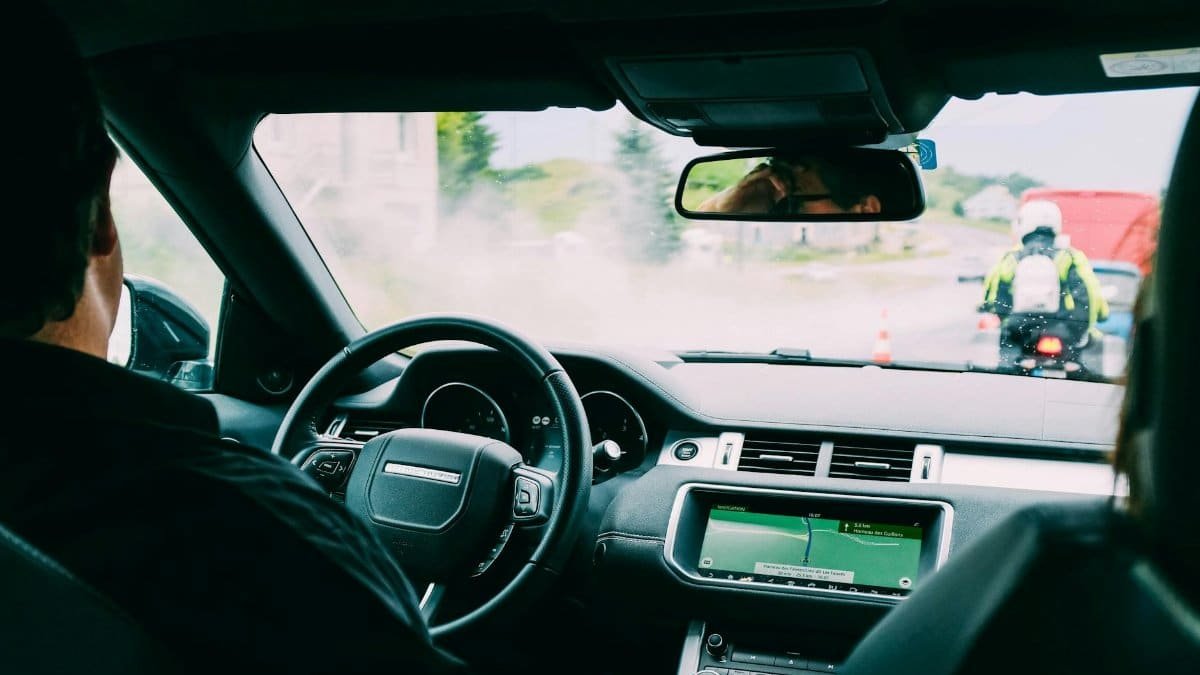 Interior view of a car with GPS navigation and traffic ahead, showcasing urban transportation.