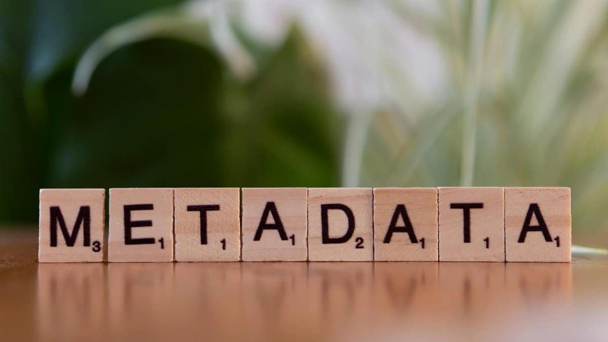Close-up of the word 'metadata' spelled out with wooden Scrabble tiles on a table.