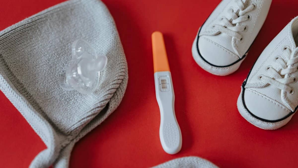 Flat lay of baby shoes, pacifier, and positive pregnancy test symbolizing new beginnings.