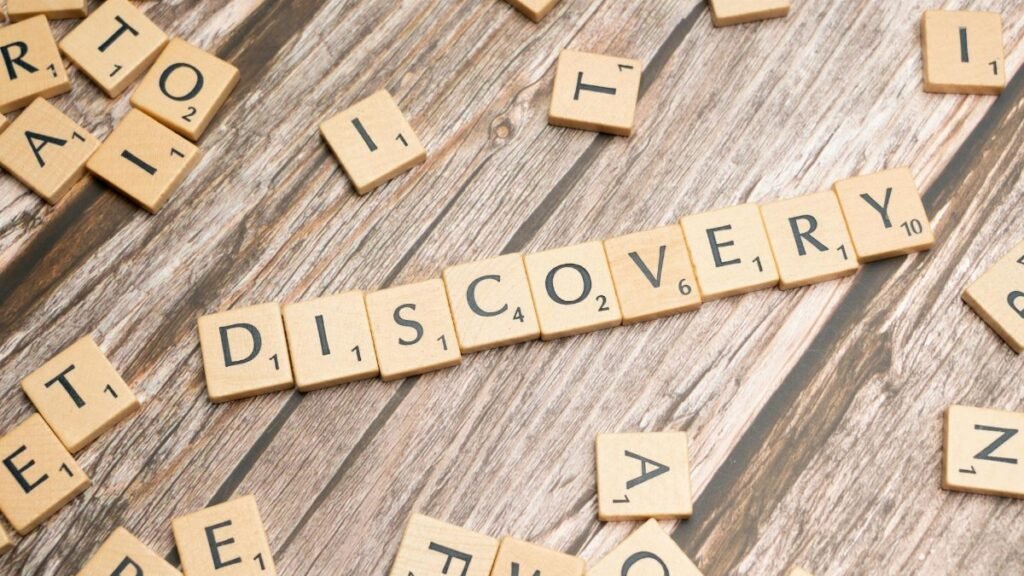 Close-up of wooden letter tiles on a table spelling 'Discovery', representing exploration and creativity.