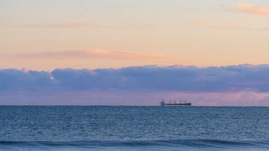 Tranquil ocean view at sunset in New Plymouth, Taranaki, New Zealand with a distant cargo ship.