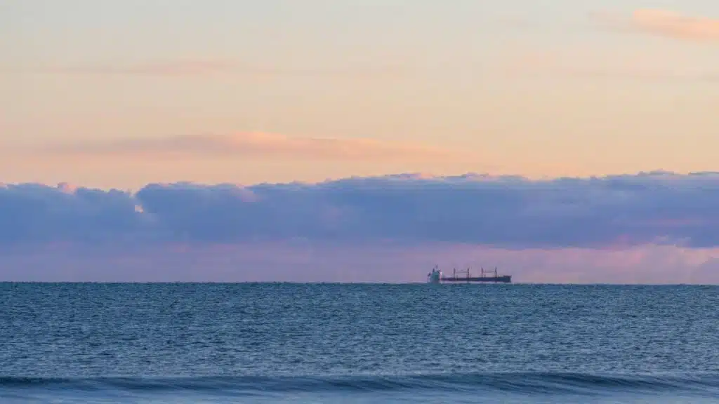 Tranquil ocean view at sunset in New Plymouth, Taranaki, New Zealand with a distant cargo ship.