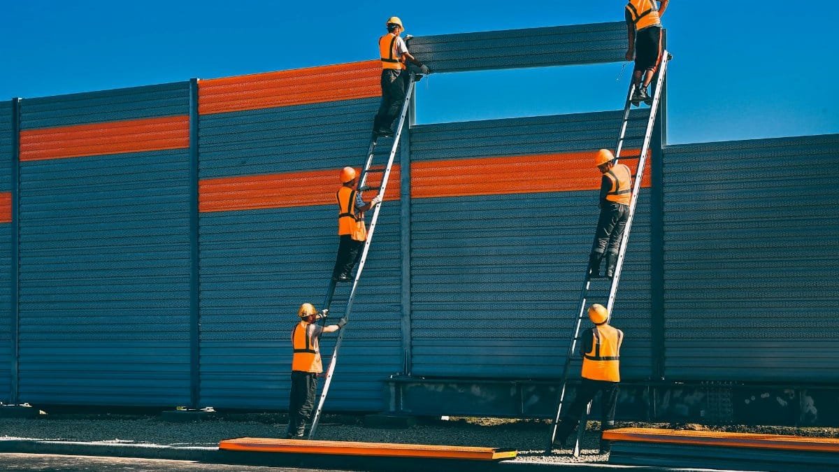 Workers in safety gear install a noise barrier on a highway in Moscow.