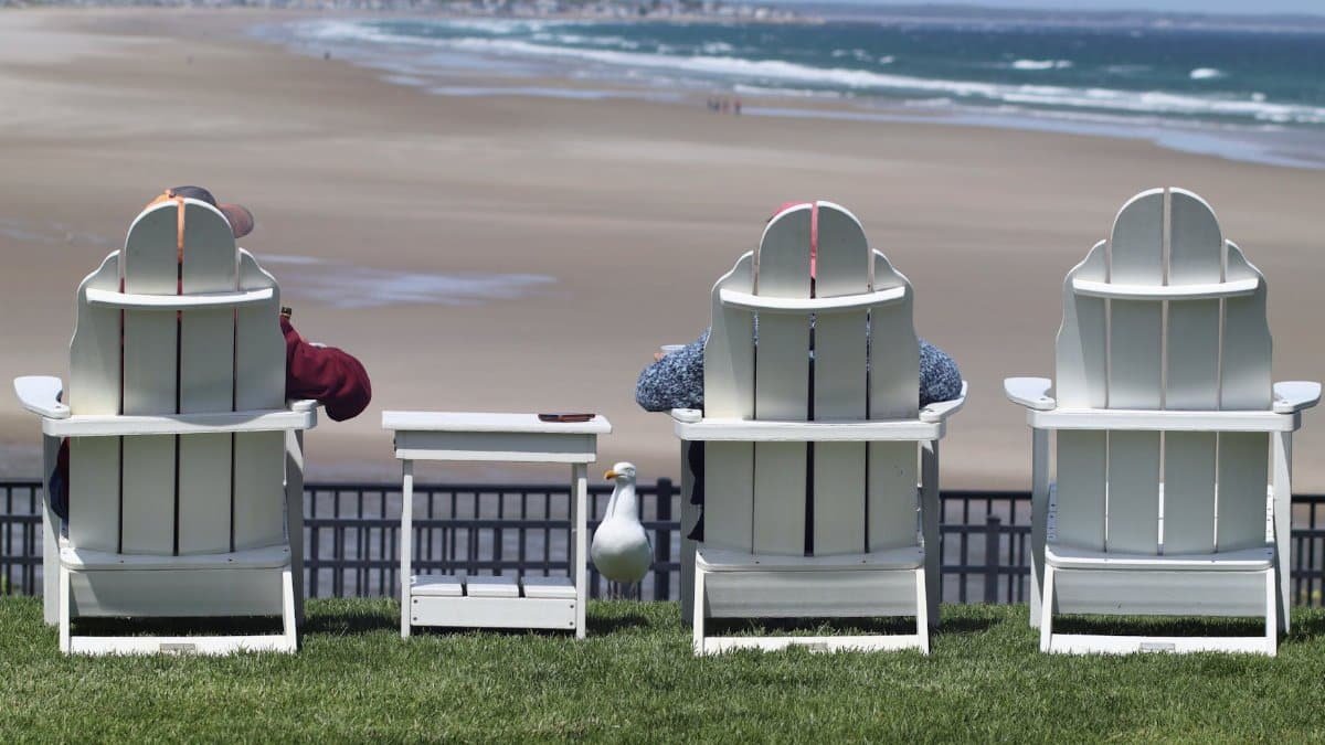 Two people sitting on beach chairs enjoying the scenic view of Ogunquit beach in Maine.