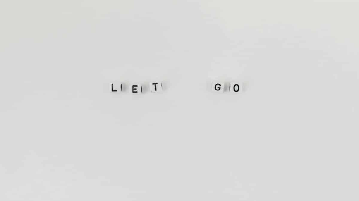 Minimalist composition featuring 'Let Go' spelled with letter dice on a clean white background.