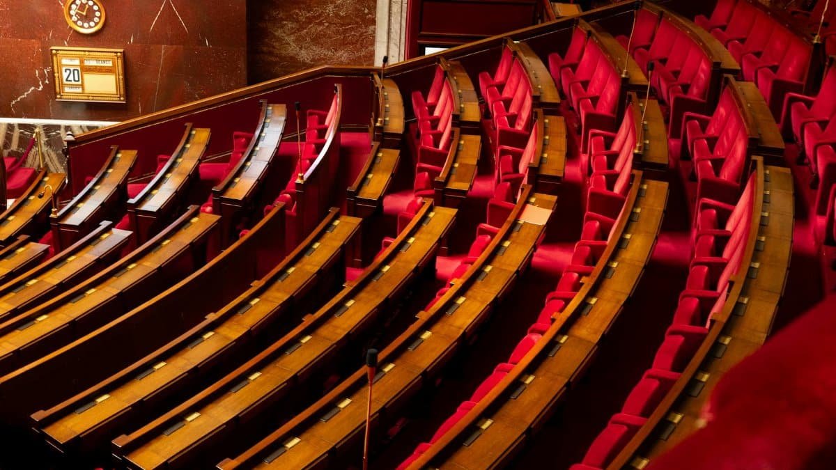 A luxurious interior view of a legislative chamber with curved red seating and wooden desks.