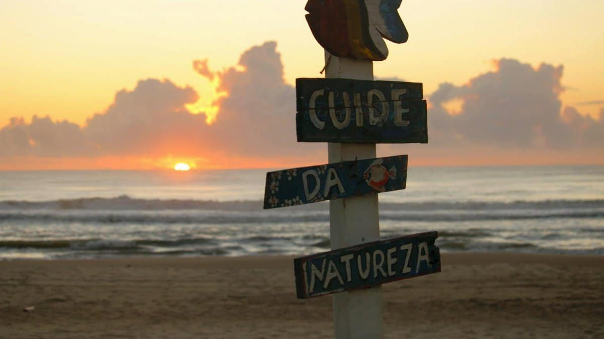 Sunrise by the ocean with a nature-conserving sign in Guaratuba, Brazil.