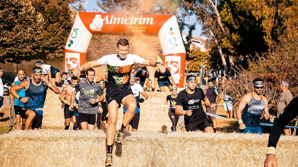 A group of male athletes race over haystack obstacles during a competition in Almeirim.