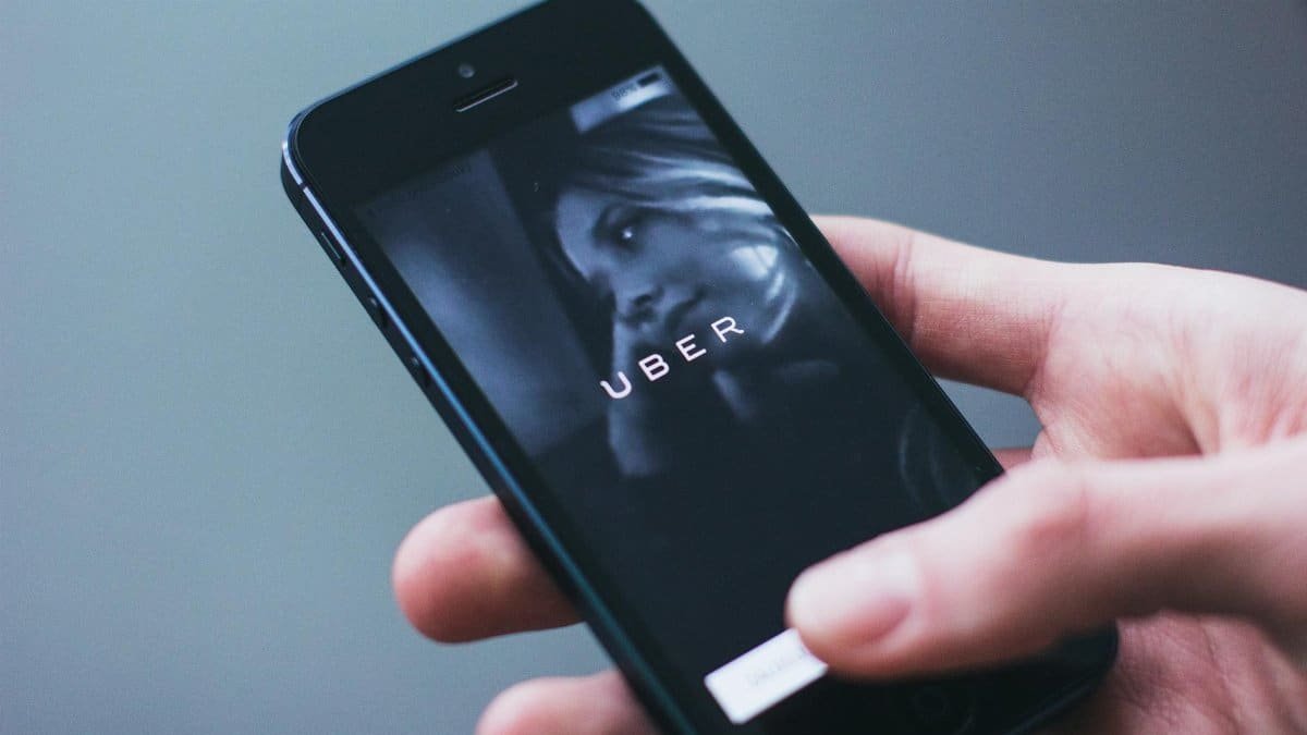 Close-up of a hand holding a smartphone with the Uber app open on the screen.