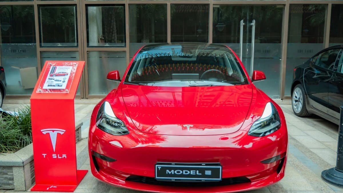 A stylish red Tesla Model 3 parked in an urban area, showcasing its sleek design and luxury features.