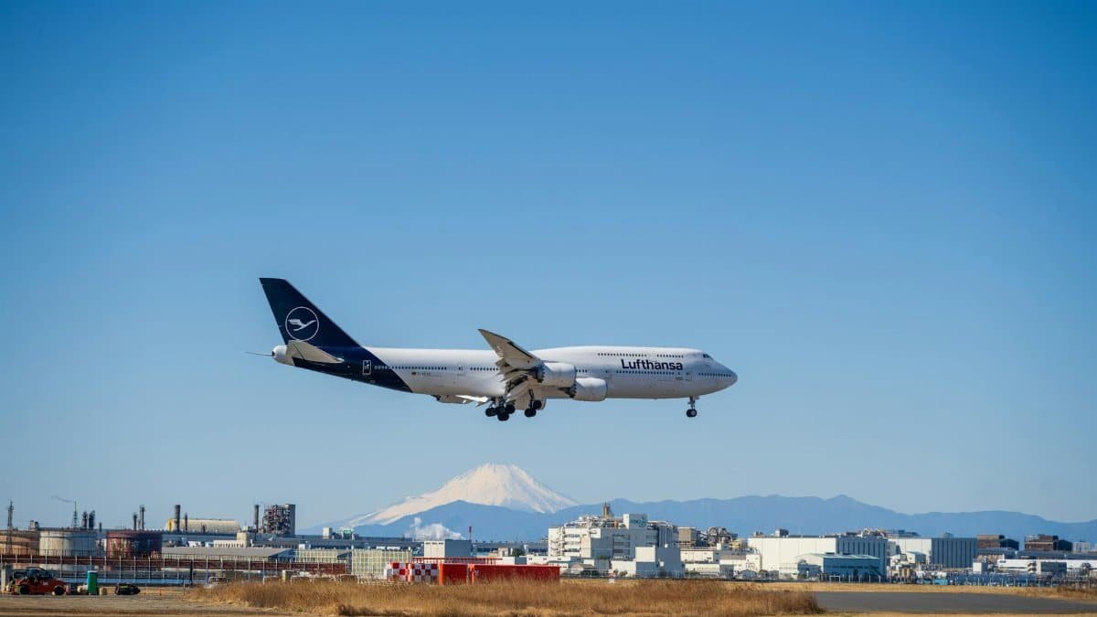 A Lufthansa Boeing 747 landing at an airport with Mount Fuji visible in the background on a clear day.