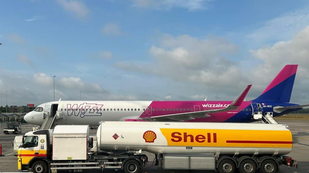 A plane being refueled by a Shell fuel truck on a sunny day at the airport.