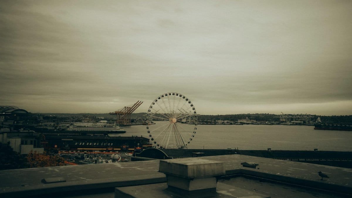 Moody view of Seattle's waterfront featuring the Great Wheel and cloudy skies.