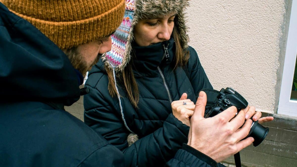 Two warmly dressed photographers reviewing camera settings on a cold day in Berlin.