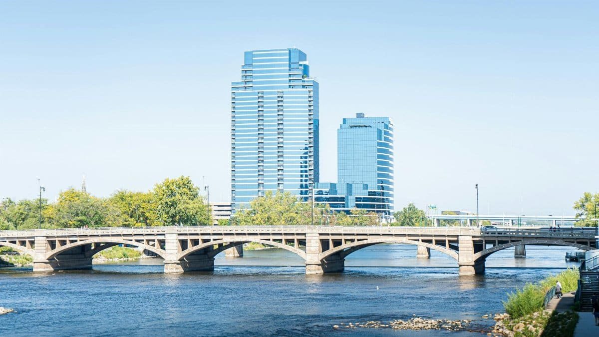 Scenic view of downtown Grand Rapids with iconic bridge and modern skyscrapers reflecting on the river.