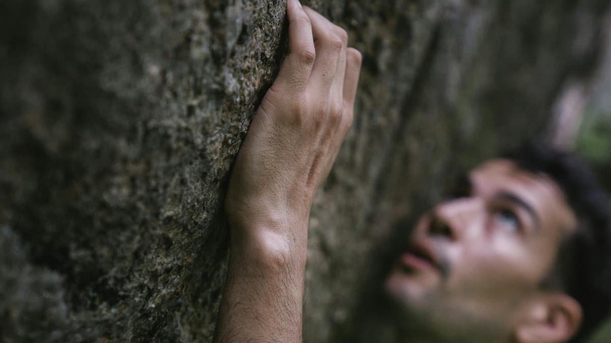 Close-up of a man climbing a rock face with focus and determination.