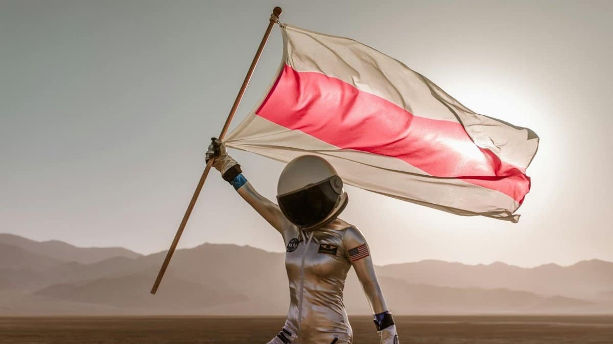 Astronaut in spacesuit holding a red and white flag in a desert setting with mountains in the background.
