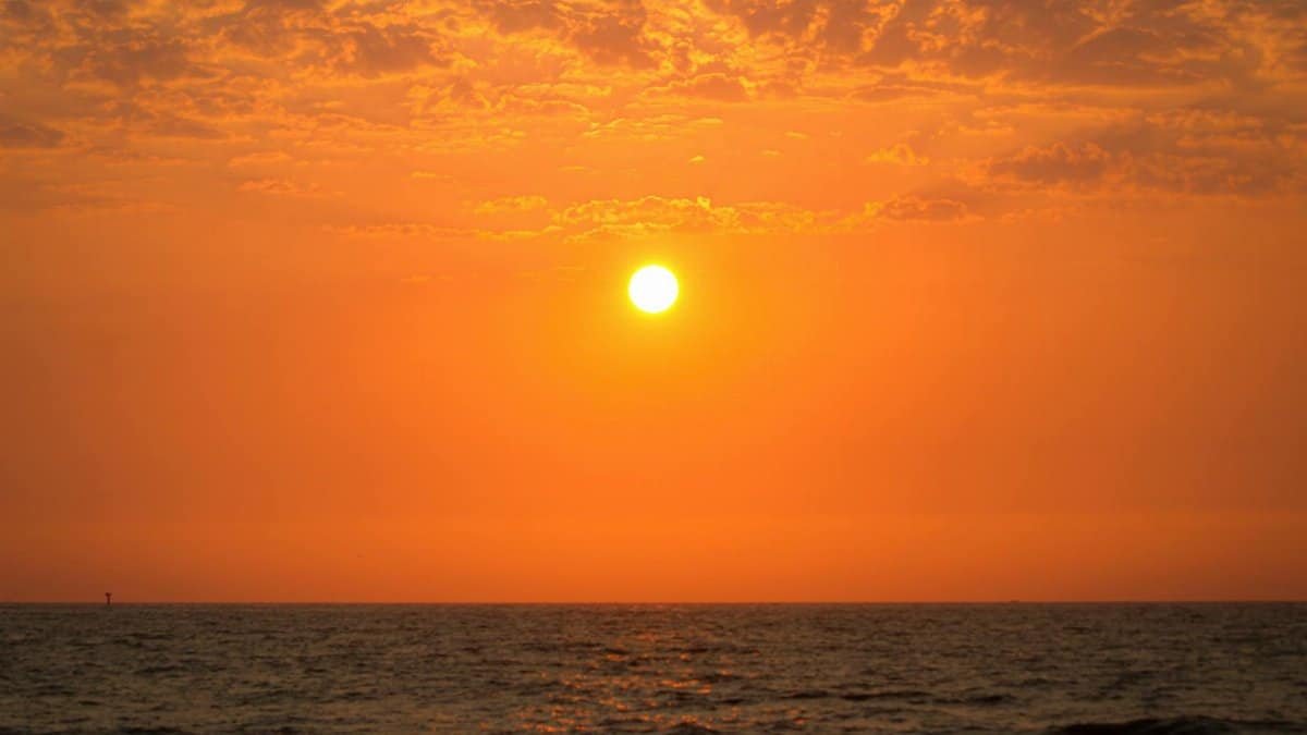 Mesmerizing sunset scene with a vibrant orange sky over a calm ocean horizon.