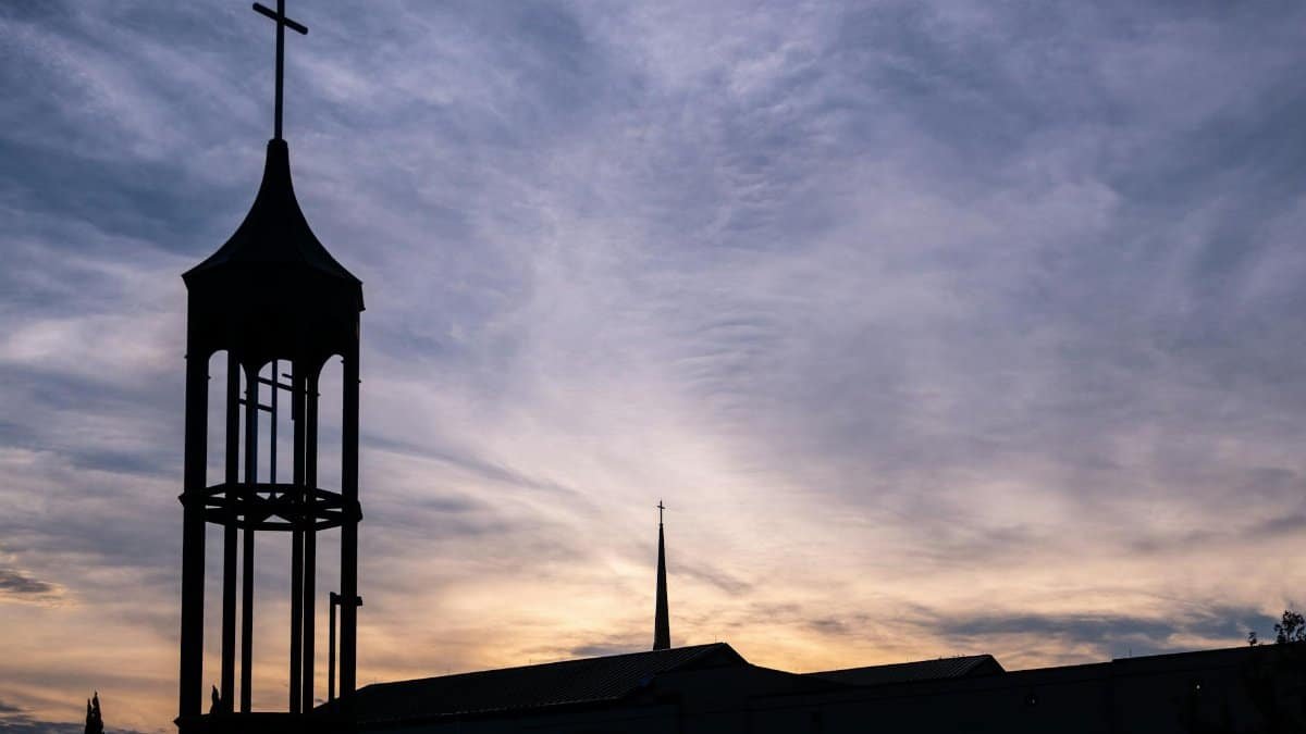 Silhouetted church tower with cross against a sunset sky in Plano, Texas.