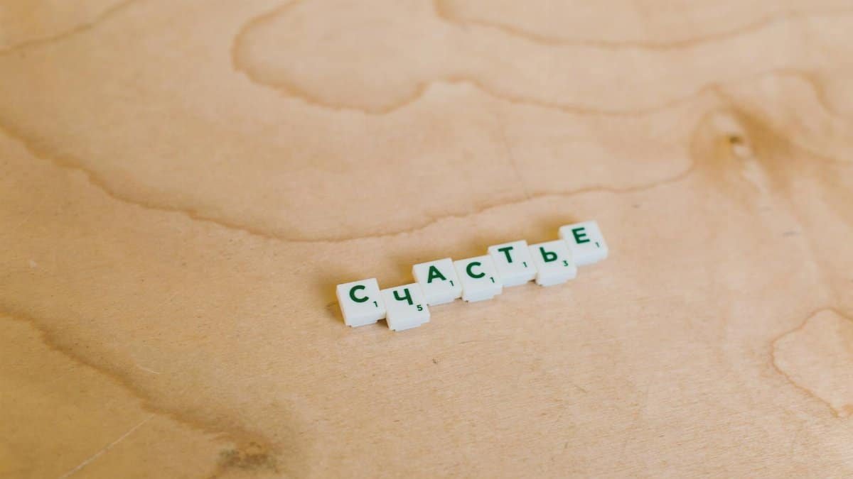 Scrabble tiles spelling Russian word on wooden surface. Creative game concept.