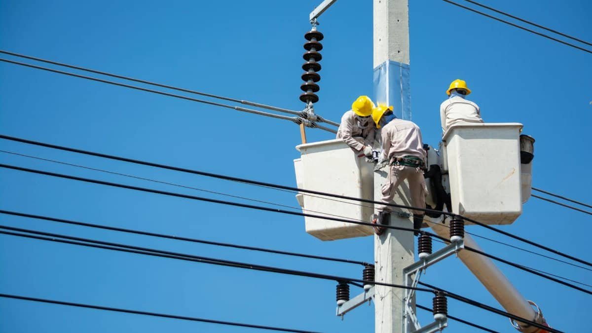 Electricians wearing safety gear work on power lines in Nakhon Ratchasima, Thailand.