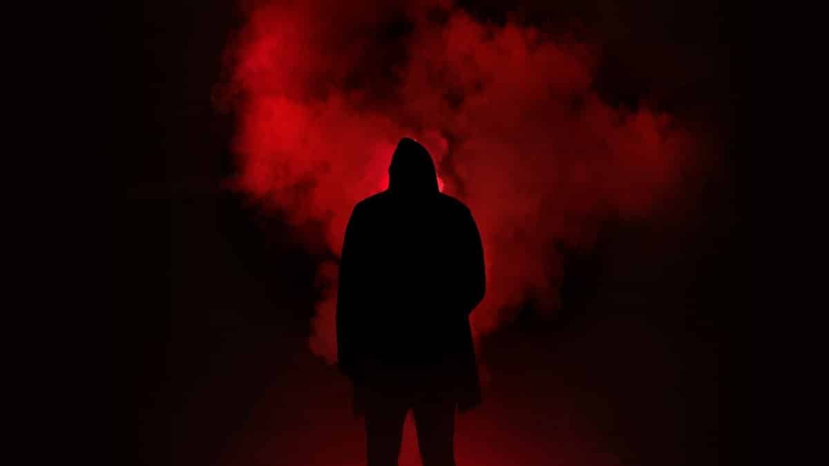 A mysterious silhouette standing against a backdrop of dramatic red smoke.
