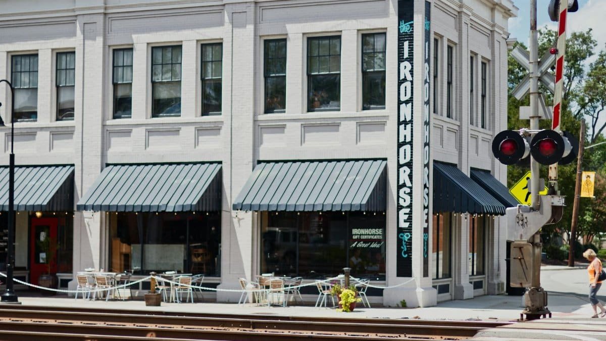 Street view of The Iron Horse Cafe at a railroad crossing, ideal for urban lifestyle imagery.