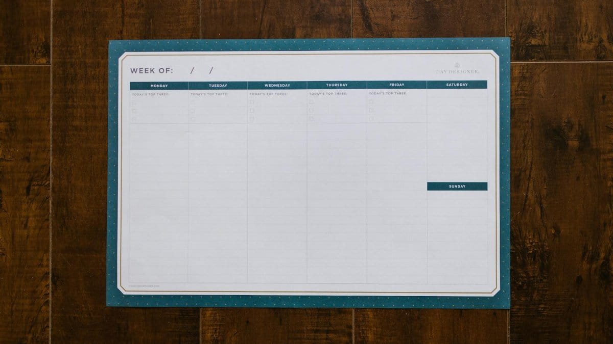 Top view of a blank weekly planner on a wooden surface, perfect for organizing your week.