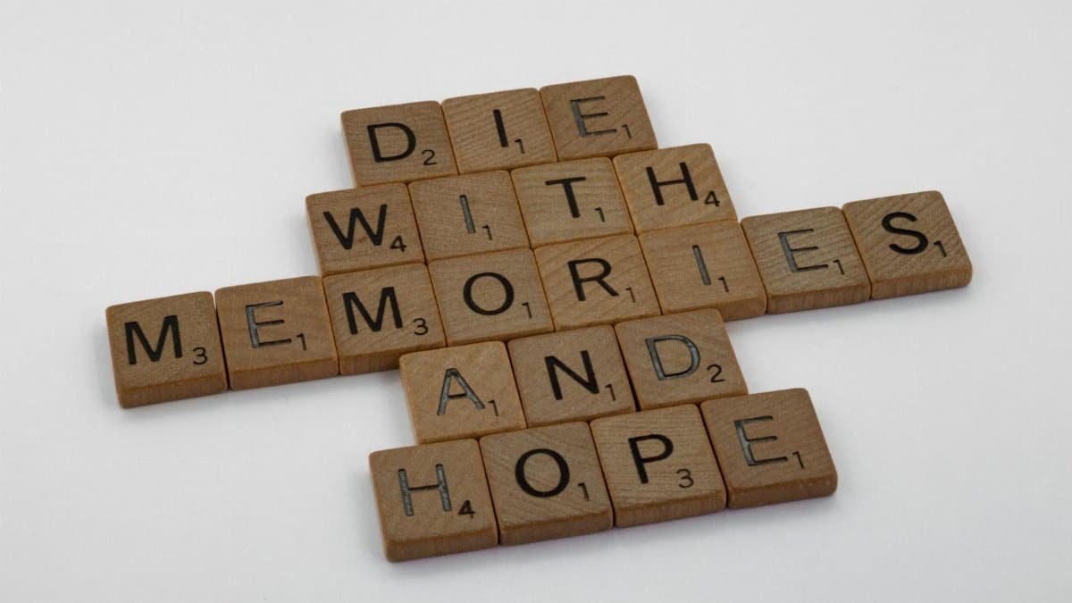 Wooden Scrabble tiles arranged to form the motivational quote 'Die with memories and hope'.