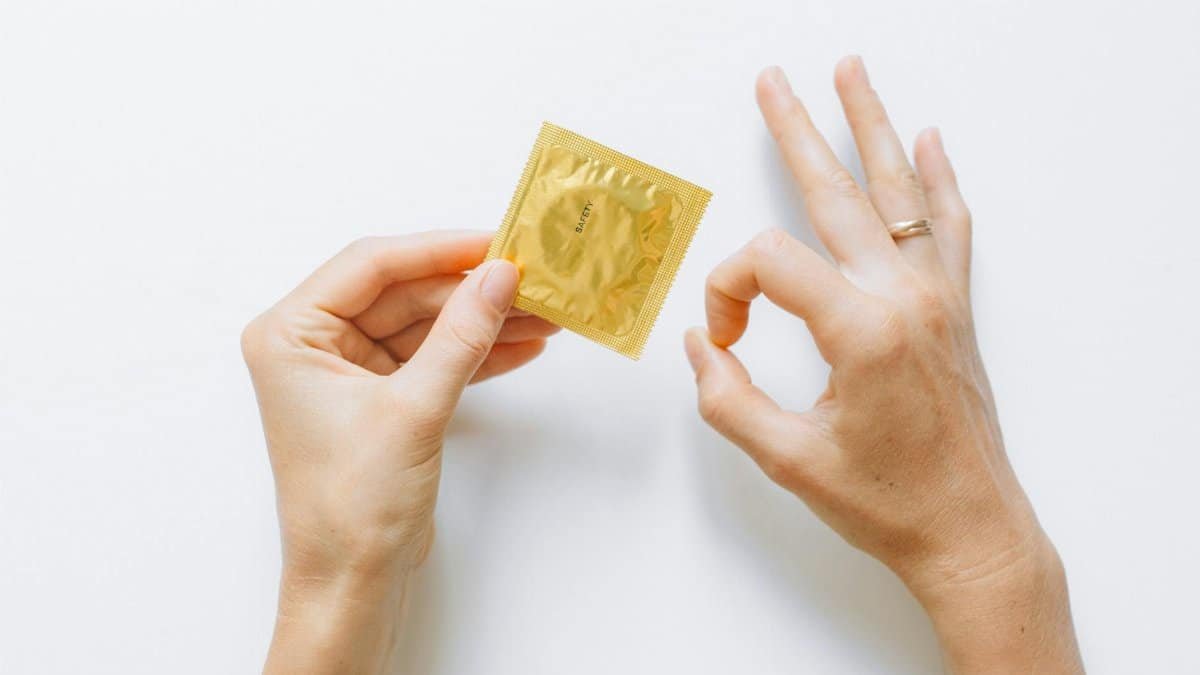 Golden condom packet held by hand, emphasizing safe sex and contraception.