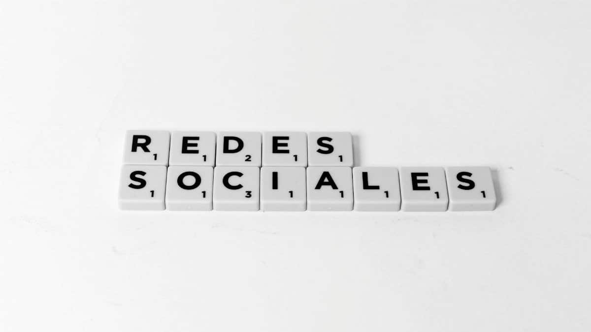 Scrabble tiles form 'Redes Sociales' on a white background, symbolizing social networks.