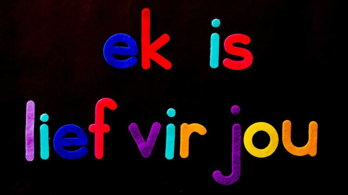 Vibrant letters spelling Afrikaans words 'ek is lief vir jou' on a black backdrop.