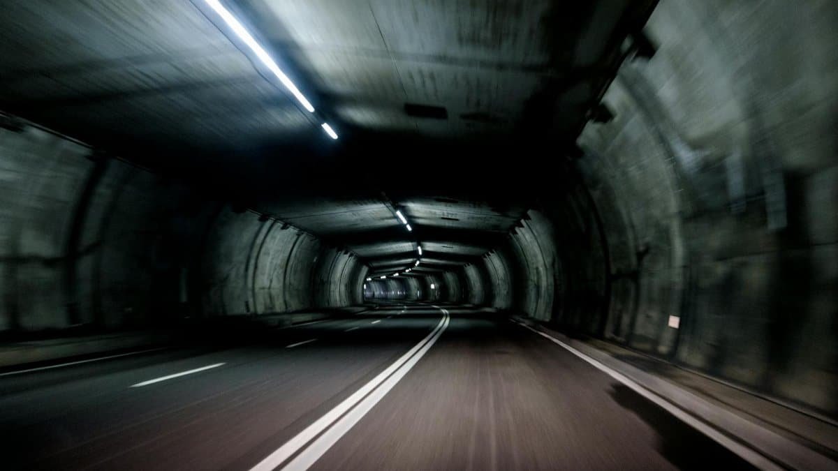Motion blur of a vehicle traveling through a dimly lit tunnel at high speed.