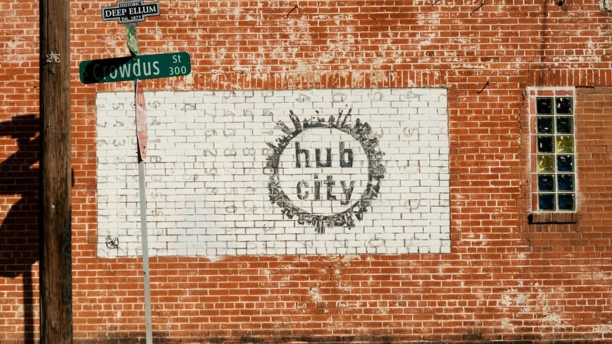 Urban street art featuring 'Hub City' mural on a red brick wall in Deep Ellum, Dallas, Texas.