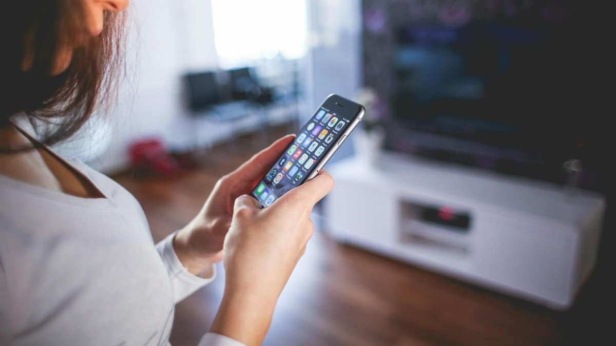 Woman browsing smartphone indoors, highlighting modern technology and communication in a cozy home setting.