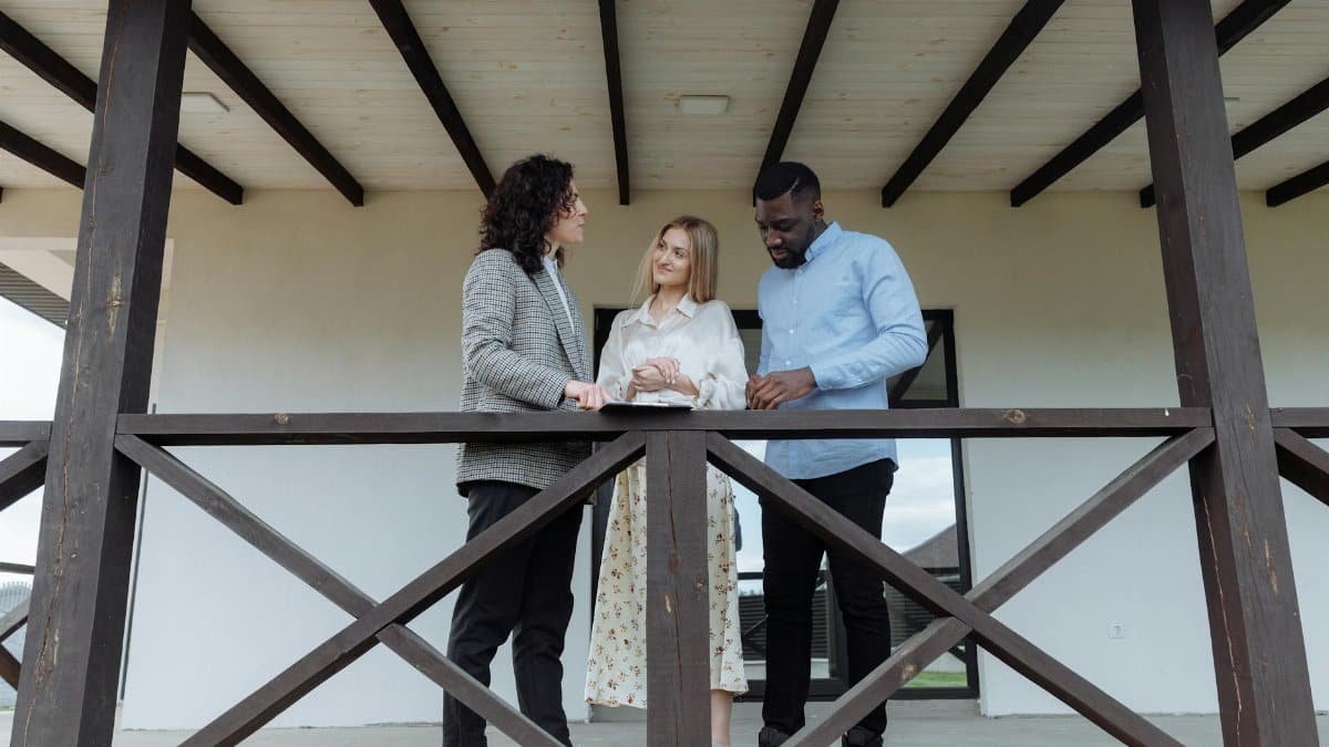 Real estate agent discussing property features with a couple on a balcony.