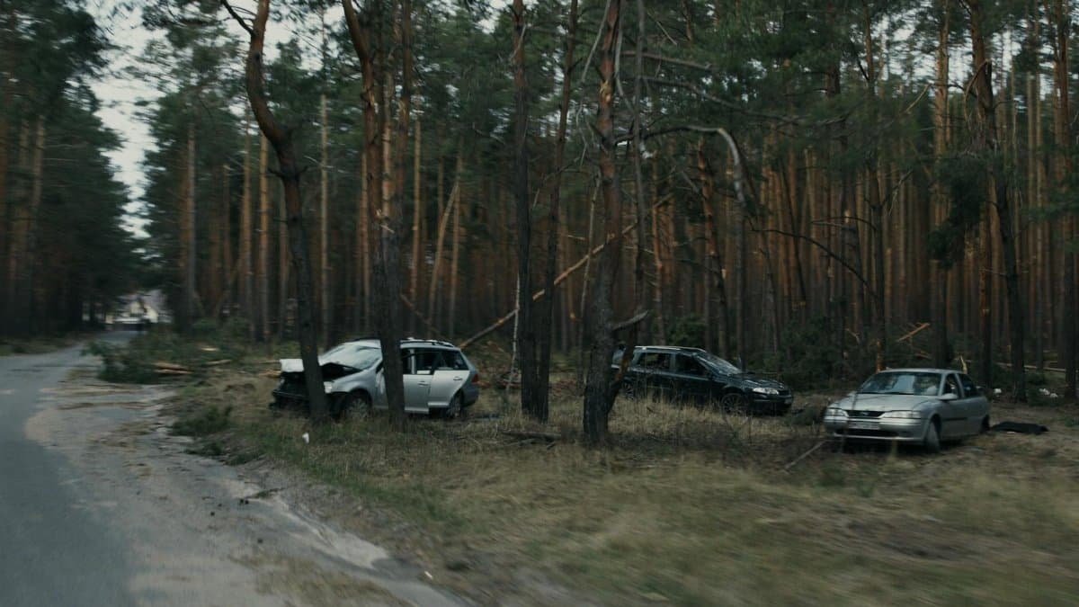 Damaged vehicles in a forested area of Kyiv, highlighting road accident aftermath.