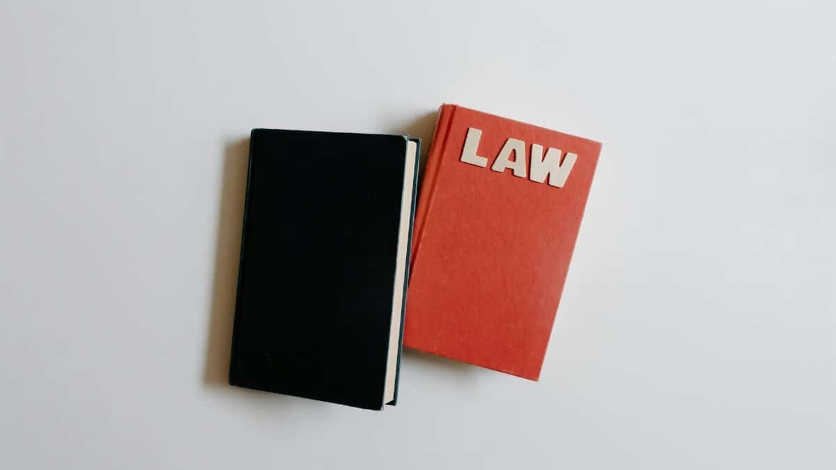Top view of a law book and black notebook on a white surface, perfect for educational themes.