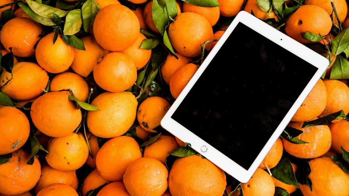 A vibrant collection of fresh oranges with a tablet, showcasing a mix of technology and nature.