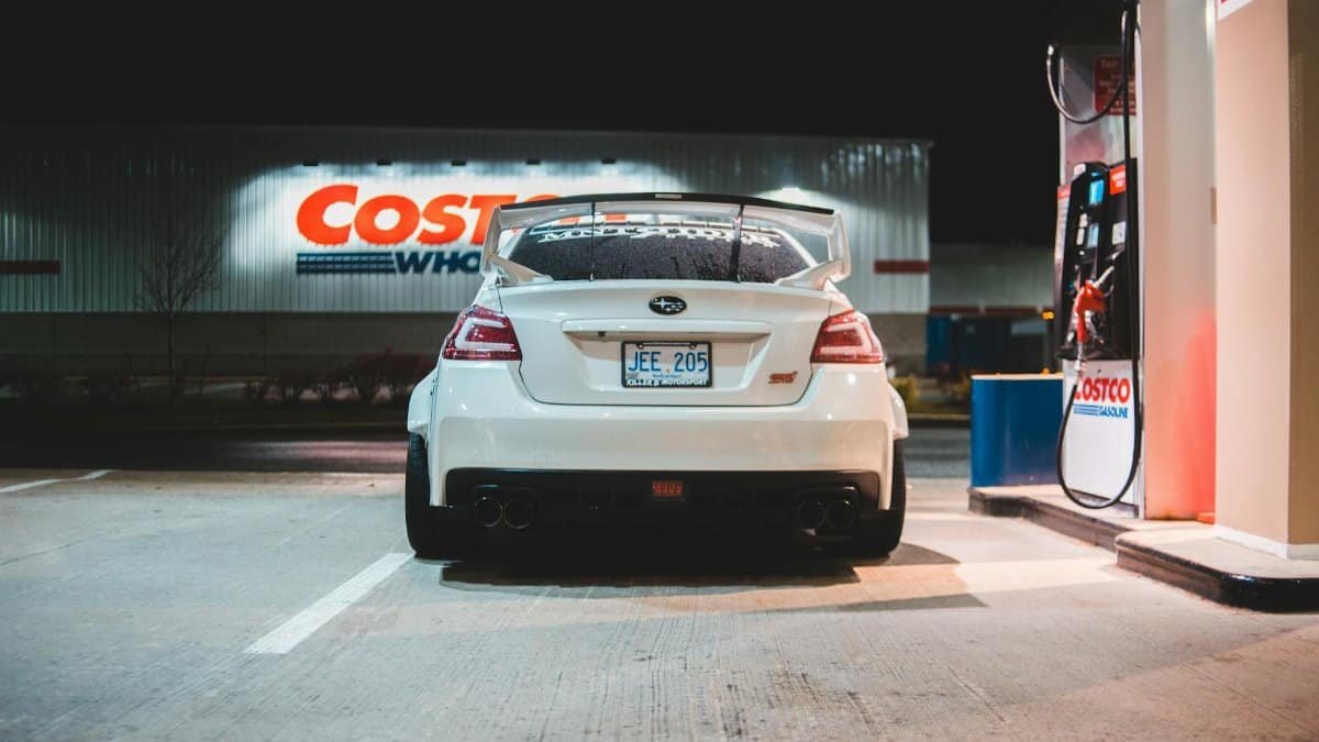 Contemporary white car parked near pump on fuel station at night in city