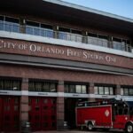 City of Orlando Fire Station One with a red fire truck outside. Clear sky and modern architecture.