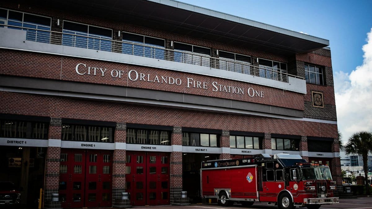 City of Orlando Fire Station One with a red fire truck outside. Clear sky and modern architecture.