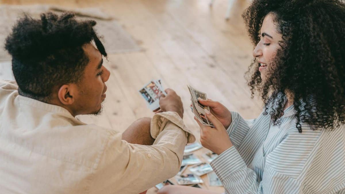 Happy couple sharing and enjoying personal photos indoors, capturing precious memories.