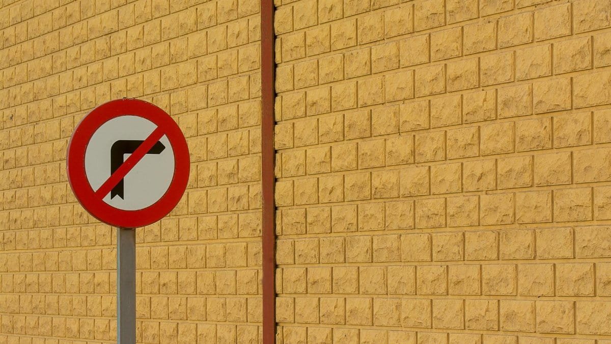 Street sign indicating no right turn against a textured brick wall, showcasing urban street design.