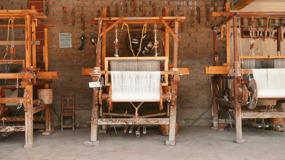 Three wooden looms in an artisan workshop in Oaxaca, Mexico, showcasing local craftsmanship.