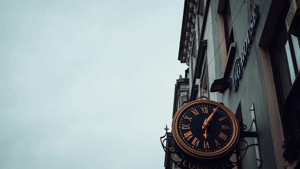 A classic clock with Roman numerals mounted on a European street building.