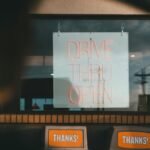 Drive thru service window with open sign at a fast food location. Daytime setting.