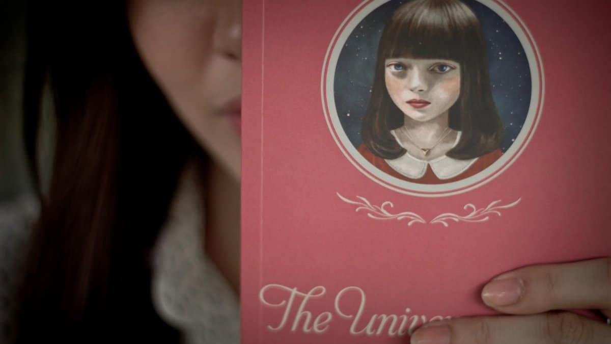 A close-up of a person holding 'The Universe of Us' by Lang Leav showcasing the book cover.