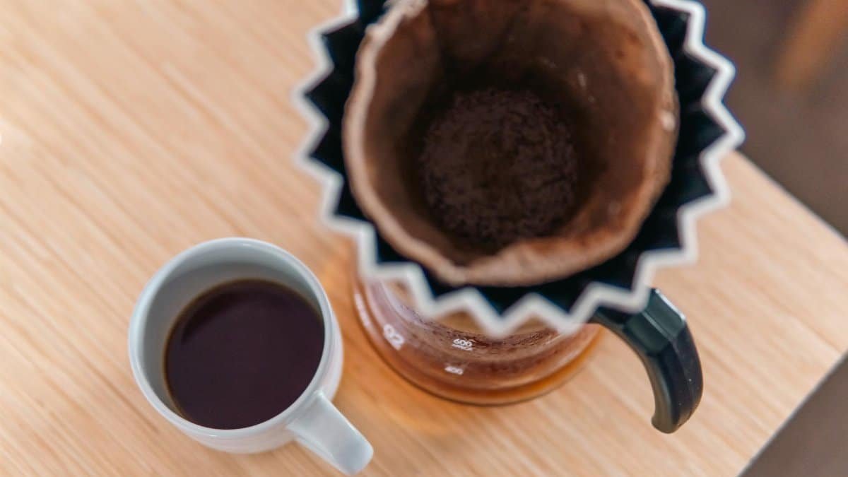 Top view of a stylish pour-over coffee setup with a fresh brewed coffee cup on wooden table.