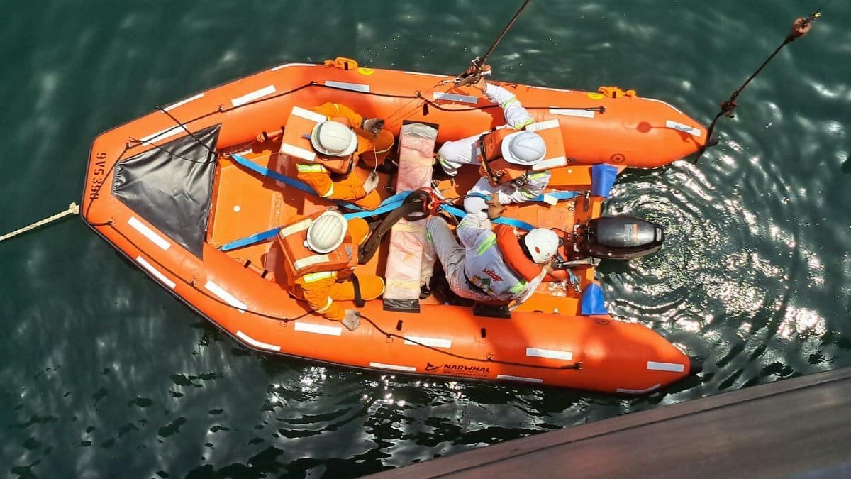 A group of people in a lifeboat conducting a rescue training drill on open water.